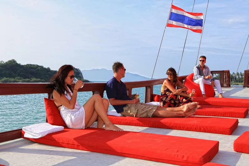 people enjoying drinks on the red baron wooden sailing junk near samui